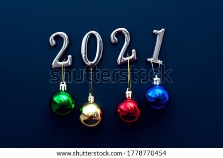 Silver numbers 2021 with colorful balls on a blue background with decorations. New Year concept, Merry Christmas and Happy New Year symbol