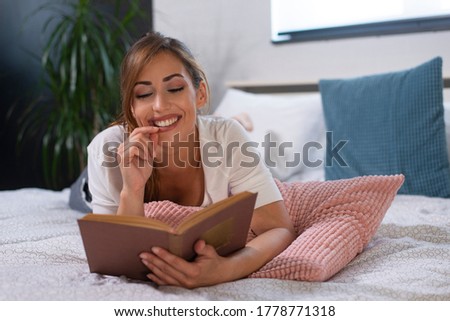 Beautiful woman lying on the bed and reading a book