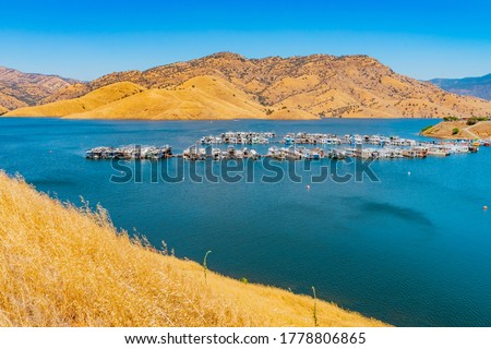 Houseboats are docked on Lake Kaweah and float on turquoise blue water. Lake Kaweah is a reservoir made from the Kaweah River in Central California that starts in the Sequoia National Park.