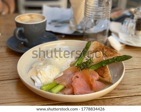 Delicious eggs Benectict with salmon and asparagus, cappuccino on the background