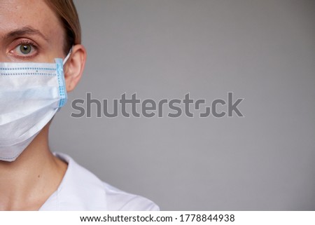 Close up of female doctor or scientist in protective medical mask over grey background