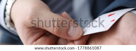 Closeup man in suit hiding ace card in sleeve. Gaining advantage in specific circumstances. Forcing to make concessions by creating deception. Identification exposure targets. Foul play Royalty-Free Stock Photo #1778861087