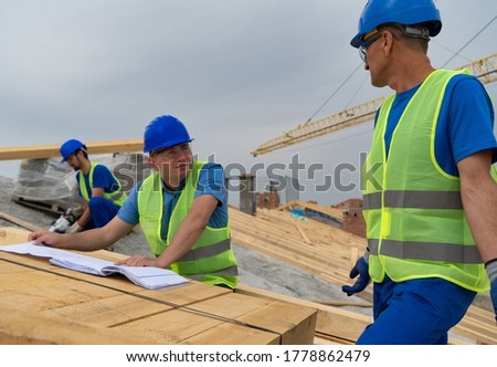 Supervisor talks to the foreman on the construction site while worker drills with the drill in the background stock photo