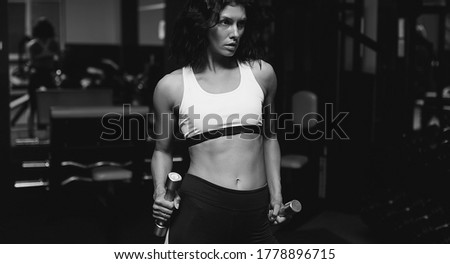 Fitness concept. Sport woman in fitness room. She doing exercises with dumbbell.