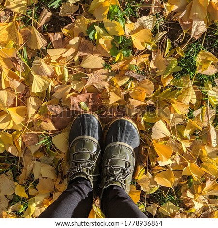lifestyle picture of person wearing duck boots on yellow orange fall autumn leaves