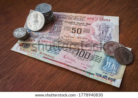 Old Indian vintage currency notes and change placed on red wooden board Royalty-Free Stock Photo #1778940830