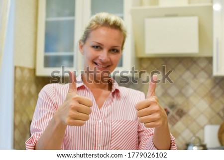 Beautiful woman housewife smiling shows approval. Buying a new kitchen for the interior.