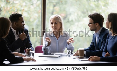 Mature 60s leader ceo company boss give helpful information to young diverse professionals teach them provide knowledge share ideas and strategic plans motivating to fruitful work, mentoring concept Royalty-Free Stock Photo #1779065786