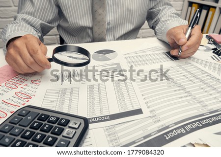 Business analysis and accounting concept - businessman working with document, spreadsheet, using calculator, tablet pc. Office desk closeup.