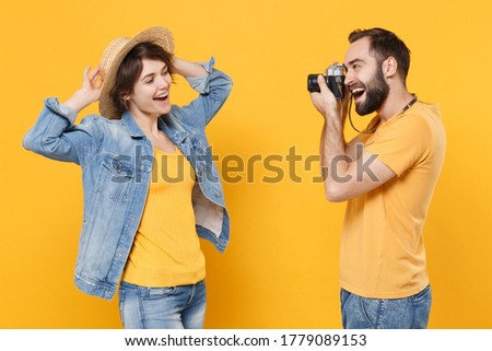 Funny tourists couple friends guy girl in summer clothes hat isolated on yellow background. Passenger traveling abroad on weekends. Air flight journey. Taking pictures with retro vintage photo camera