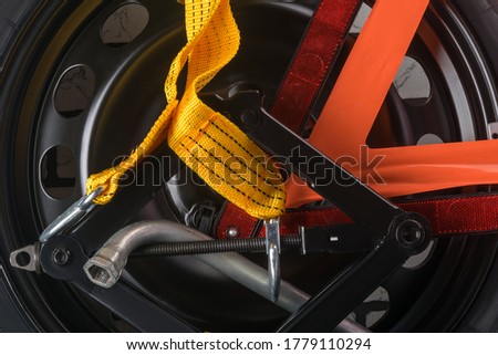 on a spare tire for a car lies a yellow tow rope and warning triangle, background