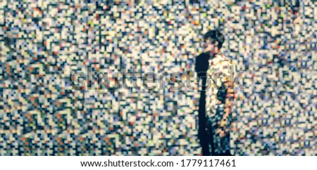 The man on the background of the projection of colored pixels. Pixels are chaotic in shape and color.