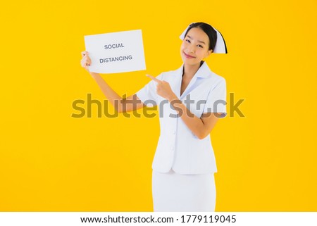 Portrait beautiful young asian woman thai nurse show social distancing sign on yellow isolated background