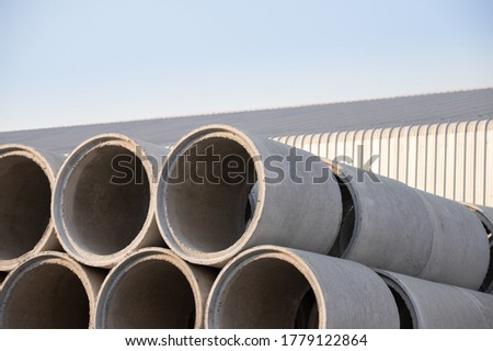 Concrete drainage pipes with factory background.