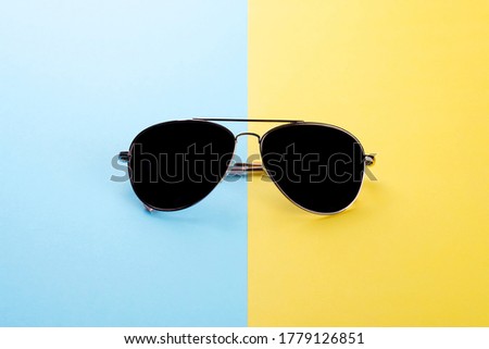 Sunglasses on blue yellow background as concept to protect eyes during summer.