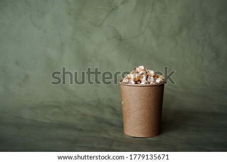 a box of popcorn on a colored background, a craft jar, fast food in the concept of minimalism, food for the cinema