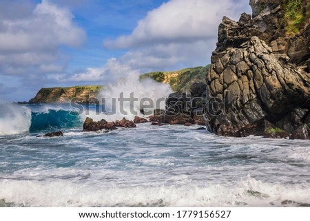 Close up shot how Atlantic ocean wave breaks on the big rocky stone on the beautiful Moinhos beach of Sao Miguel island of Azores, Portugal