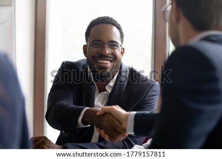 African Caucasian businessmen in formal suits express respect shake hands start negotiations. Common project growth sales increase, partnership, business etiquette, leadership, racial equality concept Royalty-Free Stock Photo #1779157811