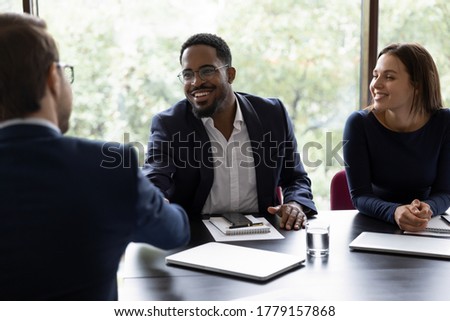 African confident executive manager welcoming client start negotiations in office. Three multiracial partners closing deal shake hands express acknowledgement and trust to future collaboration concept Royalty-Free Stock Photo #1779157868