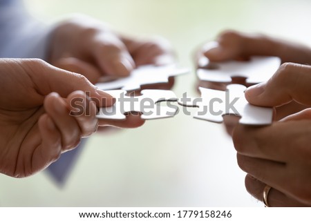 Close up hands of four businesspeople hold pieces of white puzzle, assemble jigsaw, put it together, joint path to problem solution, find way out exit of difficult situation. Support, teamwork concept Royalty-Free Stock Photo #1779158246