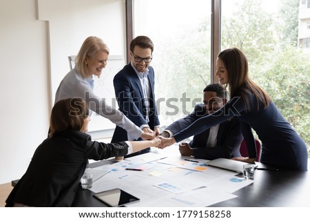 Diverse ethnicity staff accept strategic plan puts fists together make circle synergy sign, share common success, sales increase finance growth, positive forecast result, teambuilding activity concept Royalty-Free Stock Photo #1779158258