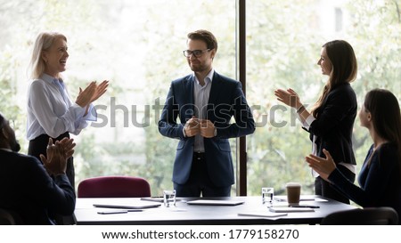Group of diverse colleagues congratulating applauding and cheering happy businessman with business achievements, career advance, great work results, job promotion standing in modern office board room Royalty-Free Stock Photo #1779158270