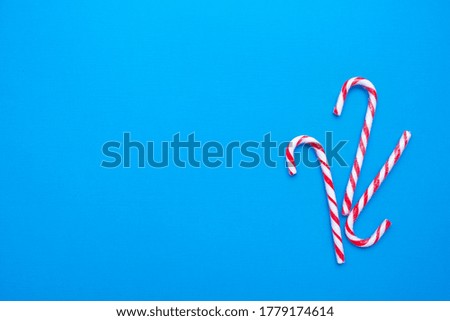 White and red candy canes on a blue background, copy space. High quality photo