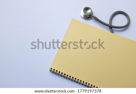 The doctor's notebook and stethoscope are on the yellow background.