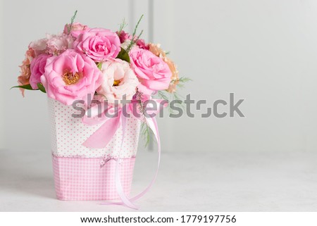 bouquet of beautiful pink roses and eustomas in a box on a white background. Floral gift for the holiday. place for text. horizontal image.