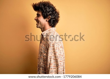 Young handsome man on vacation wearing summer shirt over isolated yellow background looking to side, relax profile pose with natural face with confident smile.