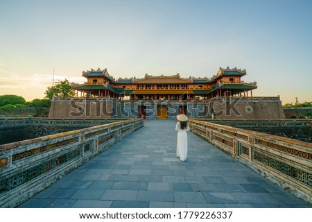 Ngo Mon gate - the main entrance of forbidden Hue Imperial City in Hue city, Vietnam, with Vietnamese girl wearing traditional dress Ao Dai Royalty-Free Stock Photo #1779226337