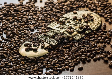 Coffee spills out of the bag onto the table. Arabica and robusta on a dark wood table. Brown color. Coffee beans scattered on the surface. Place for the text. God of Peru. Peruvian god statuette Royalty-Free Stock Photo #1779241652