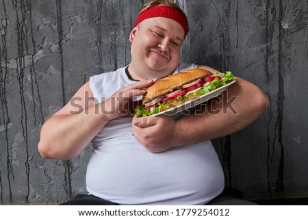 cute funny fat man stroking sandwich in hands, he treats food as something gentle, holds it as a child Royalty-Free Stock Photo #1779254012