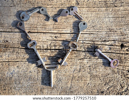 Old shabby keys on a wooden background in the form of a heart top view