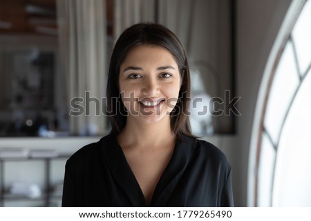 Profile picture of smiling indian young businesswoman look at camera posing at workplace, headshot portrait of happy millennial ethnic female employee show confidence, optimism, employment concept