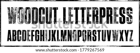 Vintage Woodcut Letterpress Condensed Display Font. Works well at large sizes. Highly detailed individually textured characters with a distressed vintage woodcut print texture. Unique design font Royalty-Free Stock Photo #1779267569
