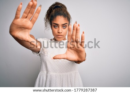 Young beautiful african american girl wearing casual t-shirt standing over white background doing frame using hands palms and fingers, camera perspective