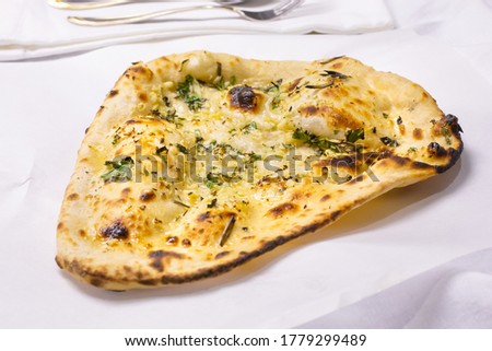 A view of a serving of garlic naan bread, in a restaurant or kitchen setting.