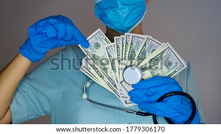 A female doctor with a medical mask, gloves and a stethoscope holds the money in her hands. Corruption in medicine. Royalty-Free Stock Photo #1779306170