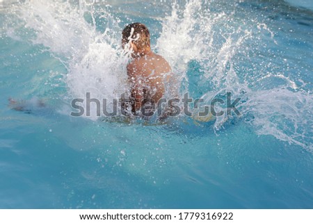 A young man jumping into water in home swimming pool. Summer sport at home. Garden swimming pool. 