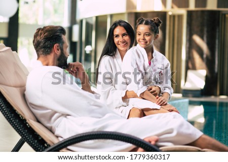 Happy beautiful family in bathrobes are joyful together while sitting in the spa salon Royalty-Free Stock Photo #1779360317