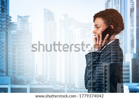 Successful smiling black African American business woman in suit pensively talking phone, Bangkok cityscape. The concept of consultants as problem solvers. Double exposure.