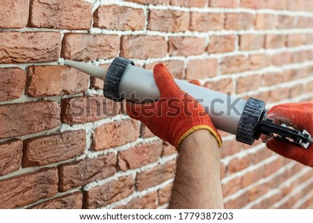 Applying grout with a syringe. Grouting decorative tile with white cement grout. Royalty-Free Stock Photo #1779387203