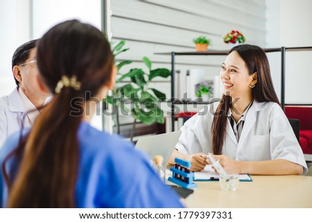 Young Asian doctors smiling and looking at medical teams while having discussion about medicine and treatment in hospital. Female doctors are discussing diagnosis and smiling during the meeting