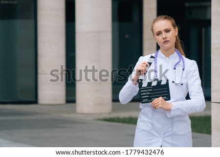 beautiful sad girl doctor with a smile holds a film strip in her hands. The concept of shooting a film about medicine. The nurse starred in the series