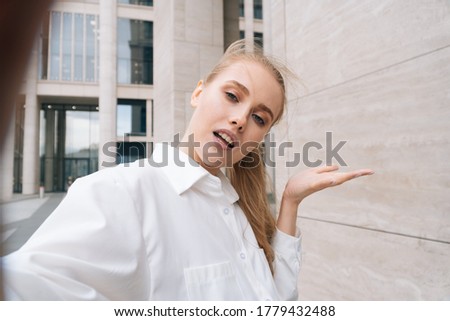 An adult woman with a sad displeased face takes a selfie on a smartphone. The concept of photography on the phone during the dialogue. Thumb down used to outrage