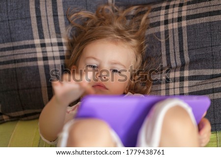 little girl lying in bed and looking cartoon on the laptop, note shallow depth of field
