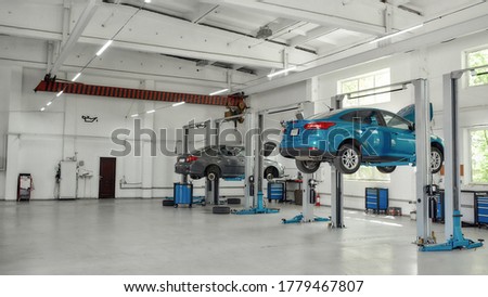 Two lifted cars at service station prepared for diagnostics and repair indoors. Car service, repair, maintenance concept. Web Banner Royalty-Free Stock Photo #1779467807