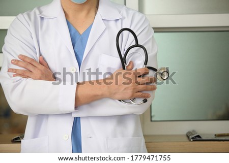 Coronavirus mask doctor wearing face protective mask against corona virus banner panoramic medical professional preventive gear.
and he hold stethoscope with hospital background