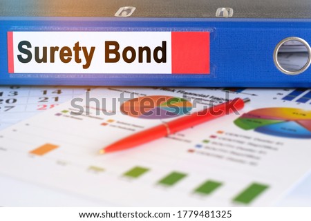 On the table are pie charts, a pen and a folder with the inscription - Surety Bond. Business and finance concept. Royalty-Free Stock Photo #1779481325